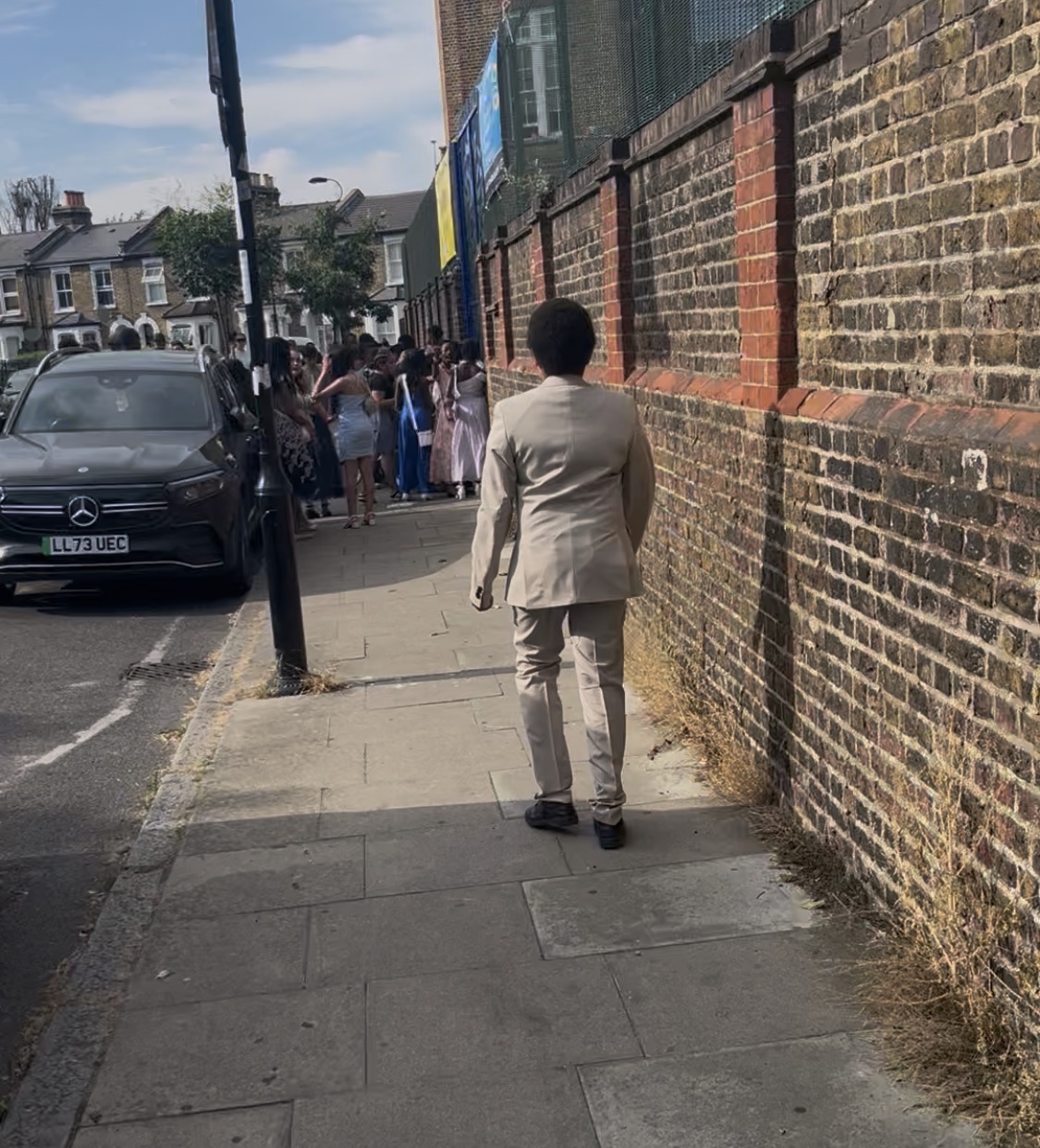 My son walking towards his year 6 prom in a cream suit.